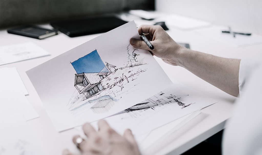 Hands holding architectural perspective sketch showing building design concept