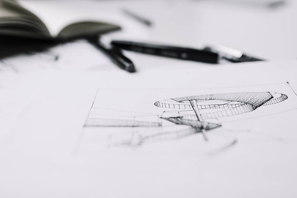 Close-up of pen on architectural sketch with drawing compass and tools