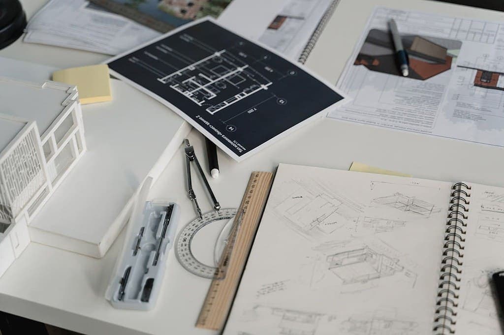 Architectural blueprints and technical drawings spread across desk with scale model