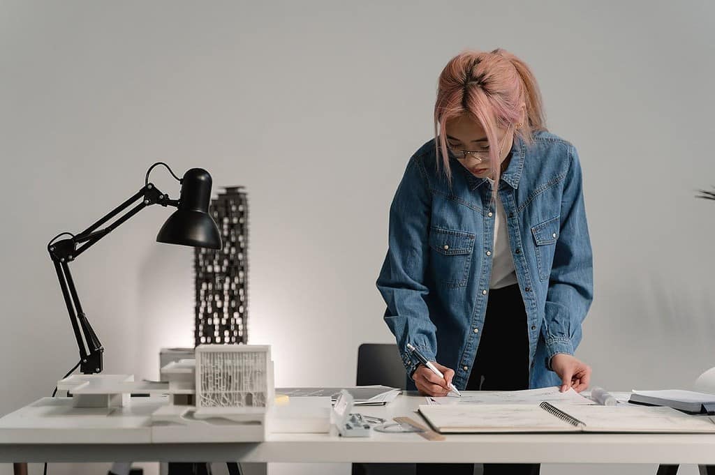 Female architect examining scale model at desk in bright studio workspace