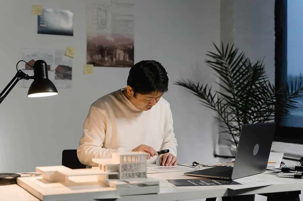 Architect focused on hand-drafting technical drawings at studio workstation