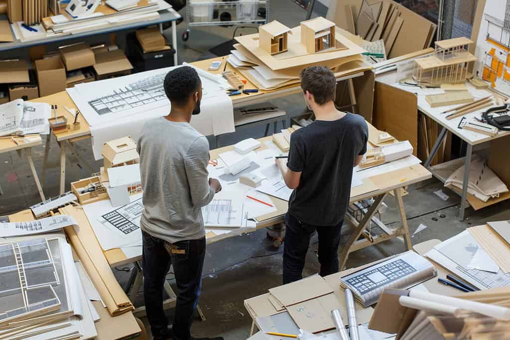Architecture school workshop showing student carefully crafting detailed physical model