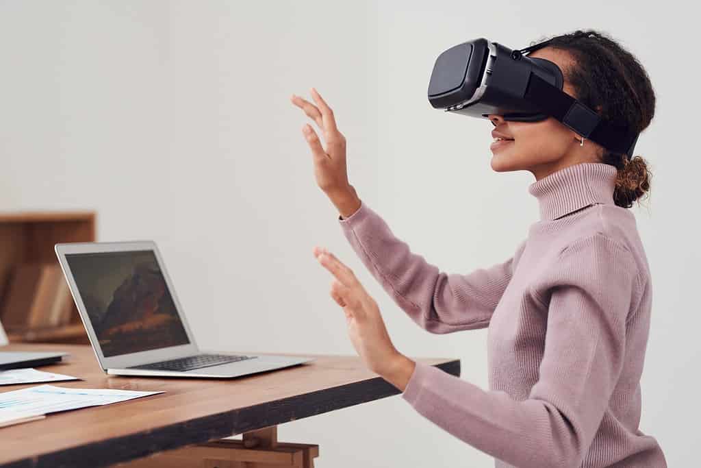Architect experiencing virtual reality design walkthrough using VR headset at office desk with laptop