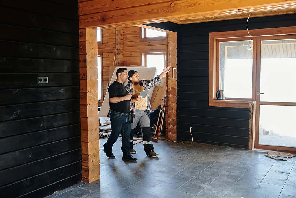 Architect and client reviewing drawings inside building under construction with exposed timber framing