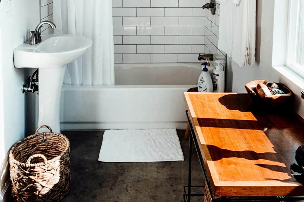 Contemporary bathroom interior design featuring freestanding bath and warm herringbone timber flooring