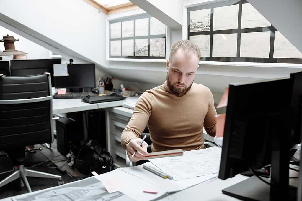 Architect presenting design concept to team members gathered around workstation in studio