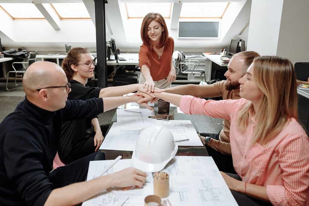 Architecture team meeting around table with hard hats indicating active construction project coordination