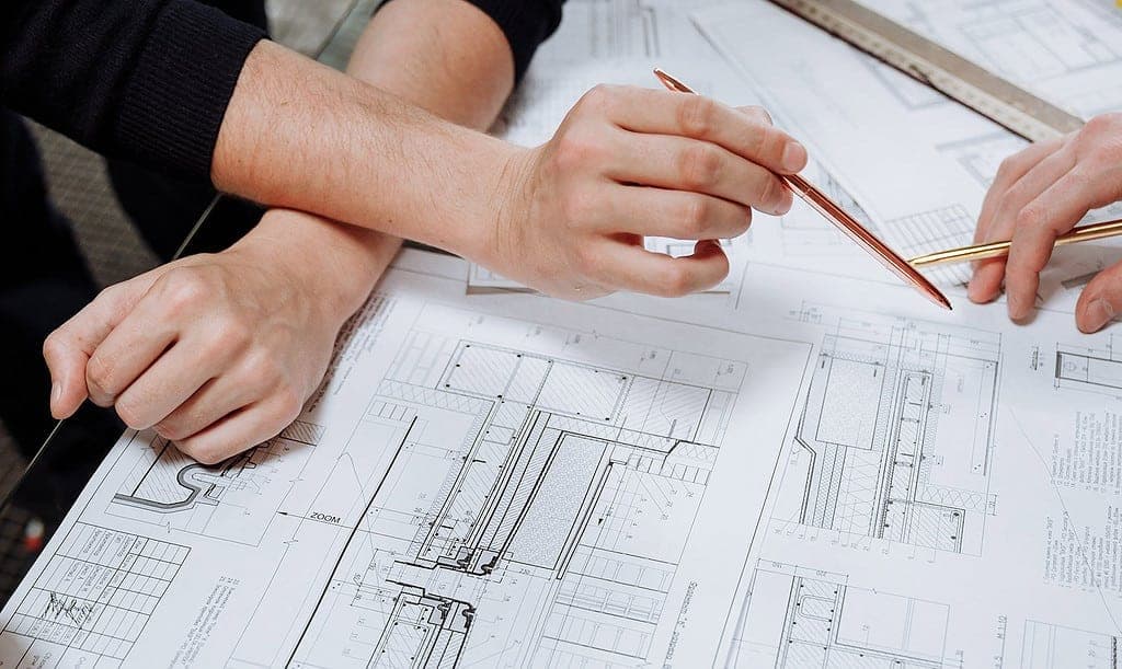Close-up of architect using compass to measure details on technical blueprint drawings